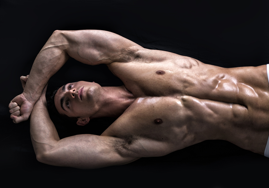 Attractive young muscle man laying on the floor with muscular ripped body