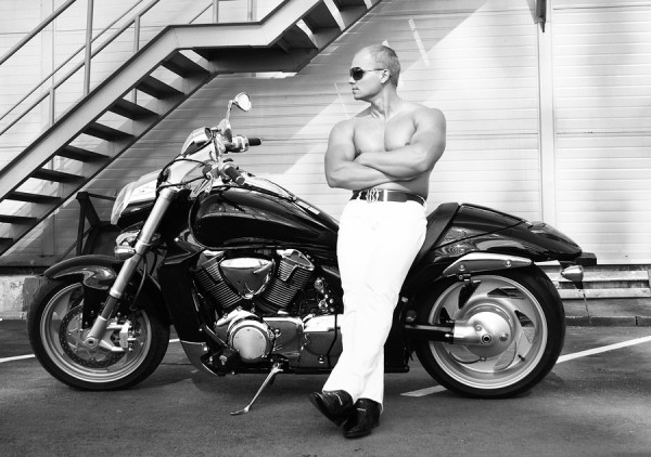 Athletically fit caucasian man sitting shirtless on a black motor bike