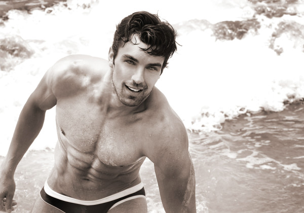 Fine art sepia toned portrait of beautiful young fit man at the beach