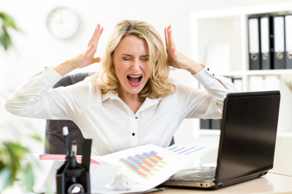 Stressed business woman screaming loudly at laptop in office