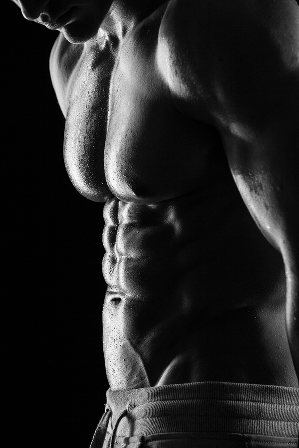 Strong Athletic Man Fitness Model Torso showing six pack abs. isolated on black background